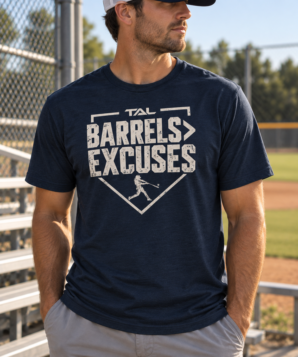 TAL Barrels Greater Than Excuses lifestyle shirt at a baseball field